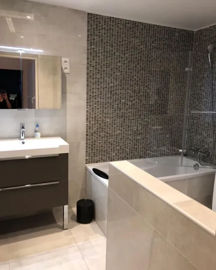 Salle de bain avec baignoire et mur en mosaïque sombre