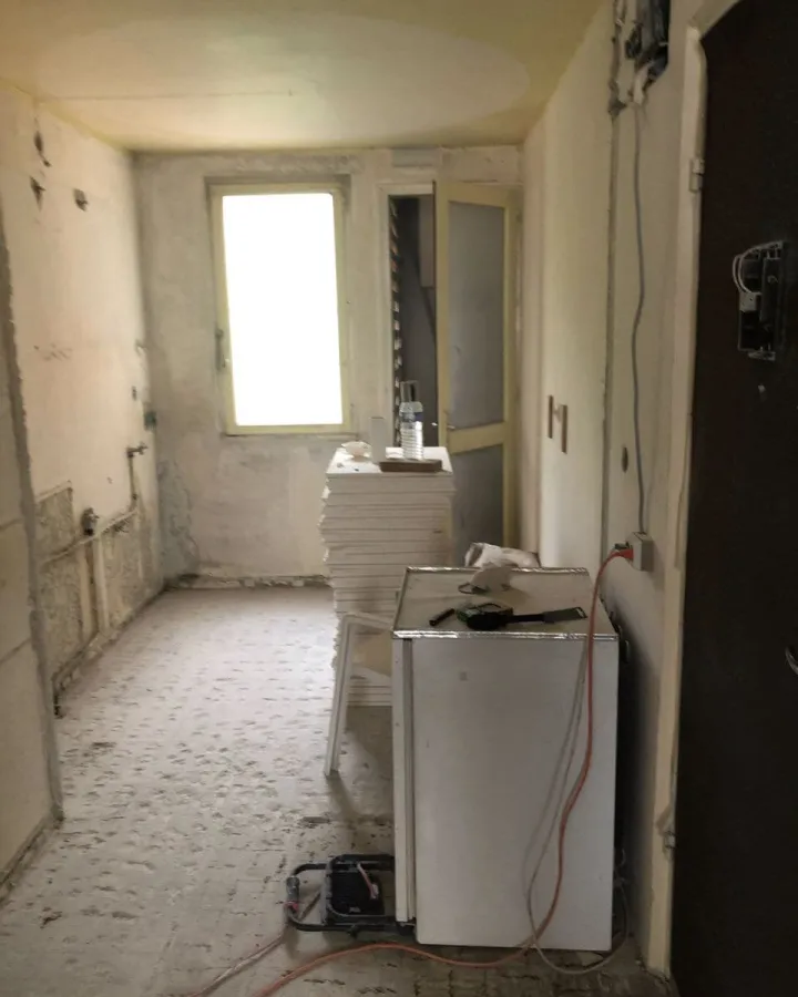 Cuisine avant rénovation, murs bruts et sol en chantier