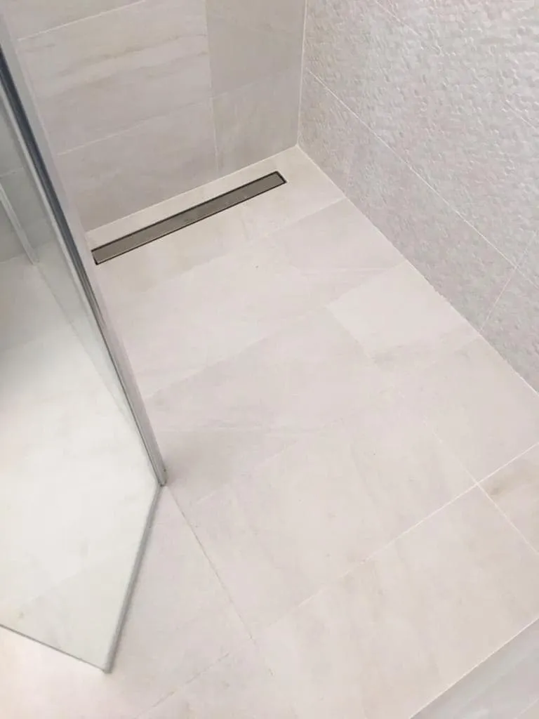 Douche à l’italienne avec caniveau, carrelage clair impeccable