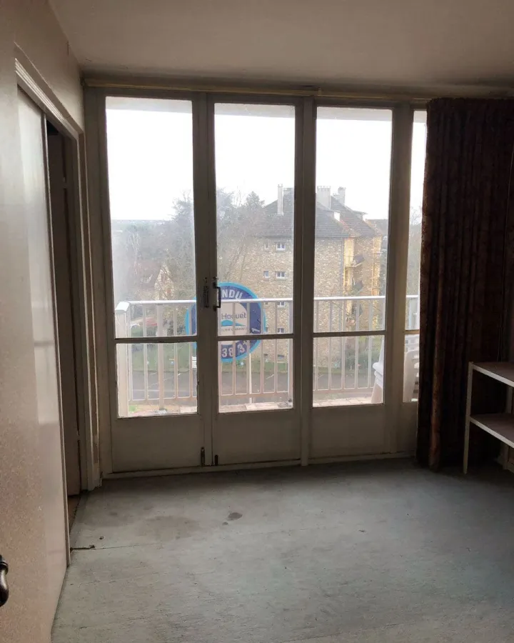 Pièce de vie avant rénovation : moquette usée et murs défraîchis